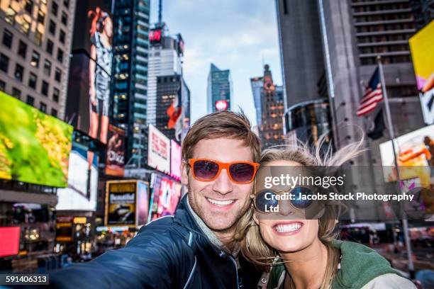 caucasian couple taking selfie in times square, new york city, new york, united states - new york tourist stock-fotos und bilder