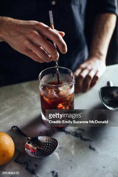 caucasian bartender mixing cocktail in glass - stirring stock-fotos und bilder