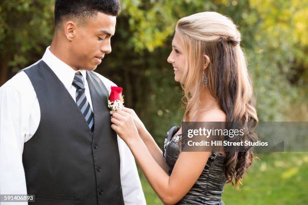 teenage girl attaching corsage to prom date - terugkomdag stockfoto's en -beelden