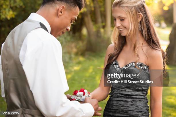 teenage boy attaching corsage to prom date - corsage imagens e fotografias de stock