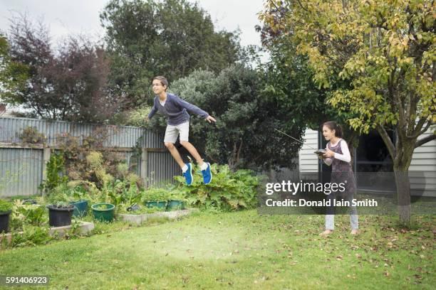 mixed race children playing with hover toy in backyard - command sisters photos et images de collection