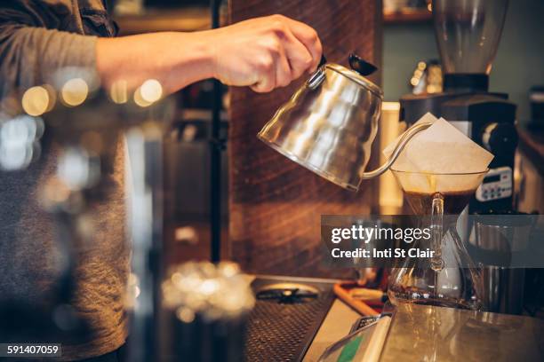 caucasian barista pouring hot water over coffee in cafe - theepot stockfoto's en -beelden