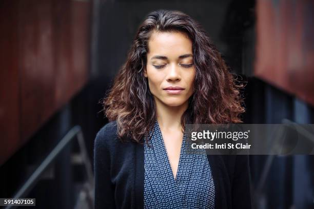 mixed race businesswoman with eyes closed in office - eyes closed imagens e fotografias de stock