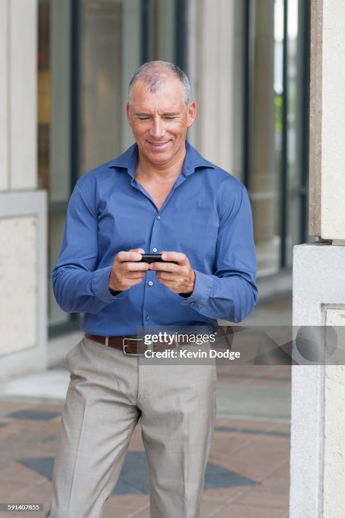 Caucasian businessman using cell phone on city sidewalk