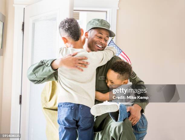 returning soldier hugging children at door - marineinfanterie stock-fotos und bilder