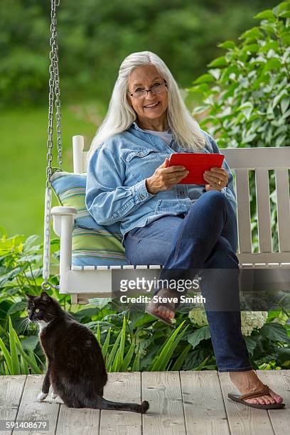 caucasian woman using digital tablet on porch swing - swing chair stock pictures, royalty-free photos & images