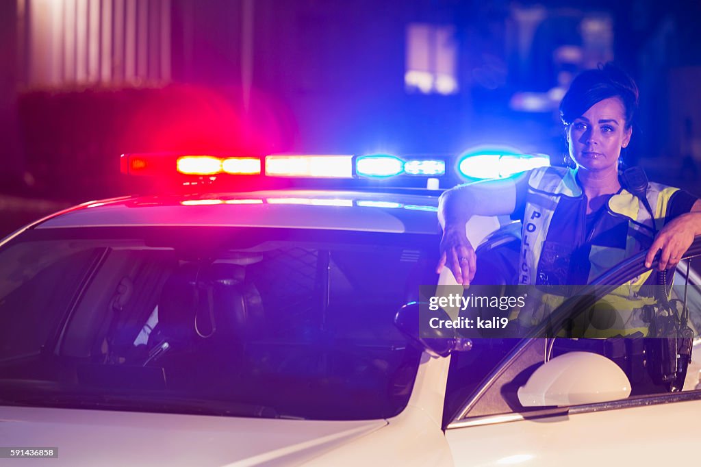 Mujer policía por la noche, las luces en socorrista de