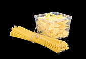 Uncooked farfalle pasta in plastic tray and long pasta