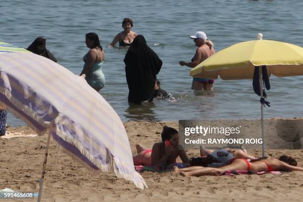 Photo taken on June 4, 2015 shows two Muslim women wearing Chador as they enjoy their time with other people a beach of Narbonne, southern France. -...