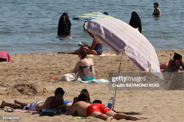Photo taken on June 4, 2015 shows two Muslim women wearing chador as they enjoy their time with other people a beach of Narbonne, southern France. -...