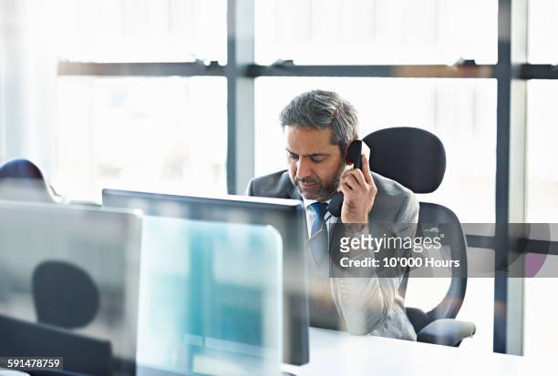 businessman talking on the phone in modern office - telefono fijo fotografías e imágenes de stock