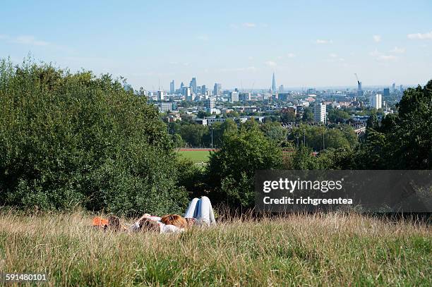 young couple lying on the grass in parliament hill - hampstead heath - fotografias e filmes do acervo