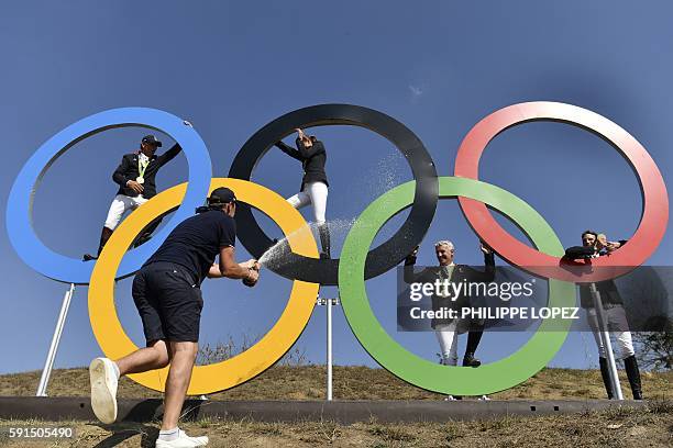 Gold medallists, France's riders Philippe Rozier , Roger Yves Bost , Penelope Leprevost and Kevin Staut, celebrate as they pose with the Olympic...