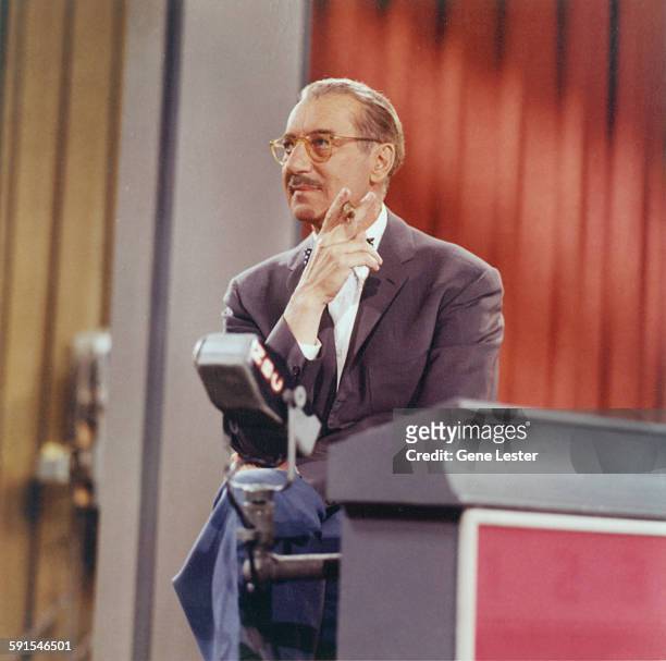 American comedian Groucho Marx holds a cigar as he hosts an episode of the television show 'You Bet Your Life' , 1950s or 1960s.
