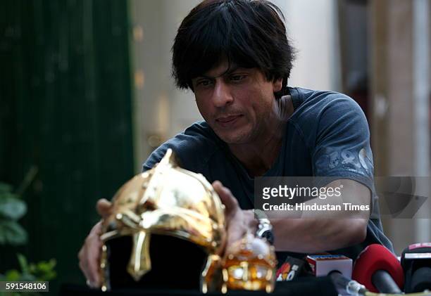 Cricket - Shah Rukh Khan unveiling the gold plated helmet trophy that will be given to the man of the match at his residence Mannat .