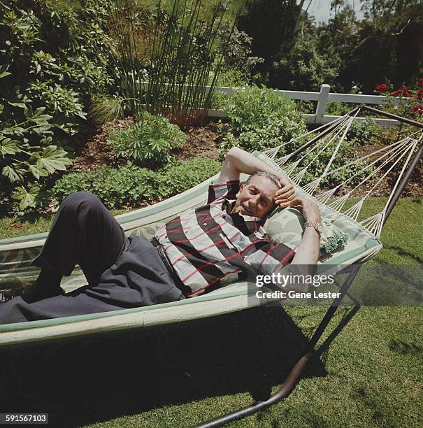 Portrait of American movie producer, artist, and animator Walt Disney as he lies in a hammock, 1950s.