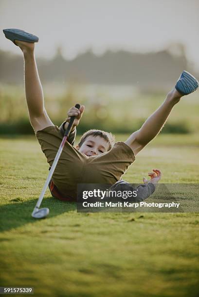 kid playing golf and falling down onto the grass - golf social stock pictures, royalty-free photos & images