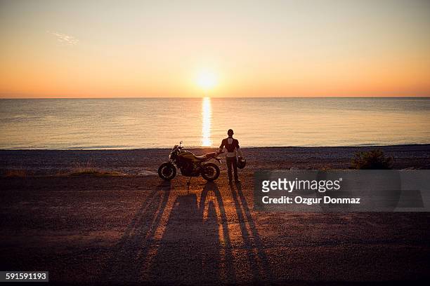 motorcycle rider on the beach at sunrise - mare moto foto e immagini stock