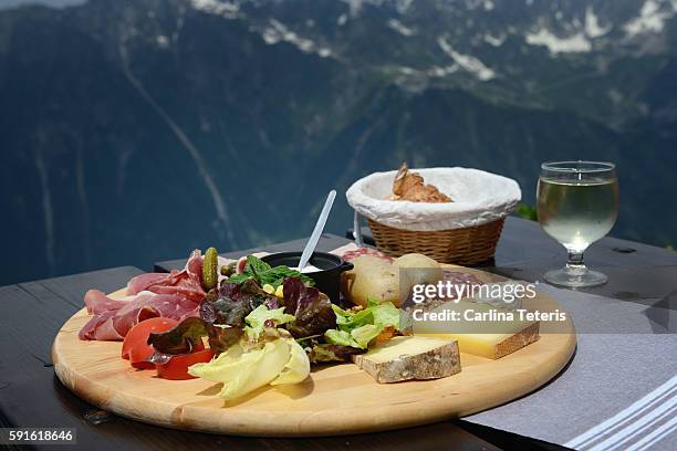 charcuterie platter and glass of white wine ona table overlooking dramatic mountain view - auvernia ródano alpes fotografías e imágenes de stock