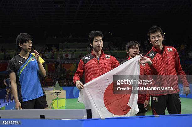 Japan's Maharu Yoshimura watches his teammates Jun Mizutani and Koki Niwa and their coach hold the national Japanese flag after losing the men's team...