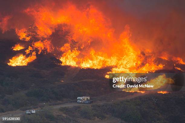 Flames close in on cars parked along a country road at the Blue Cut Fire on August 17, 2016 near Wrightwood, California. An unknown number of homes...