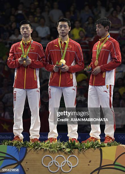 China's Ma Long, China's Xu Xin, and China's Zhang Jike pose with their gold medals after the final men's team table tennis match at the Riocentro...