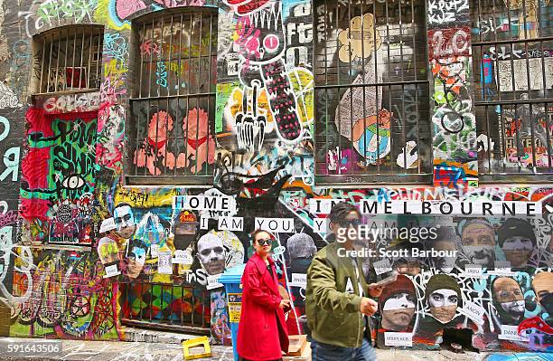 People walk past walls adorned with graffiti in Hosier Lane, one of Melbourne's iconic laneways on August 18, 2016 in Melbourne, Australia. Melbourne...