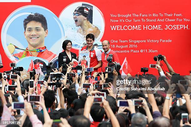 Singaporean swimmer, Joseph Schooling receives a gift from Singtel Chief Executive Officer, Chua Sock Koong during his victory parade at Singtel...