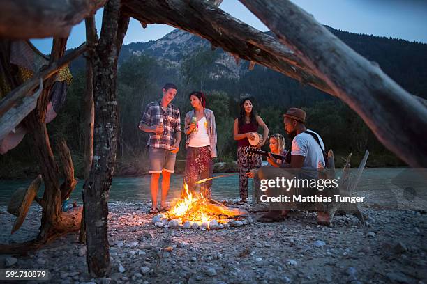 friends having a campfire in the nature at sunset - campfire stock pictures, royalty-free photos & images