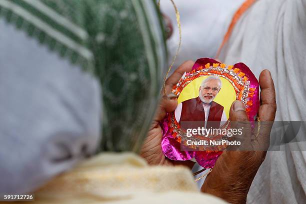 Indian widows display Rakhi with the picture of Indian prime minister Narendra Modi on the eve of the Raksha Bandhan festival at an event organised...