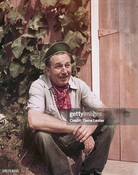 Portrait of American movie producer, artist, and animator Walt Disney as he sits outdoors, beside a wooden door, California, early to mid 1950s. He...