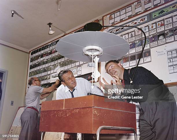 American movie producer, artist, and animator Walt Disney listens to animator Ward Kimball talk about a model for a television project, California,...