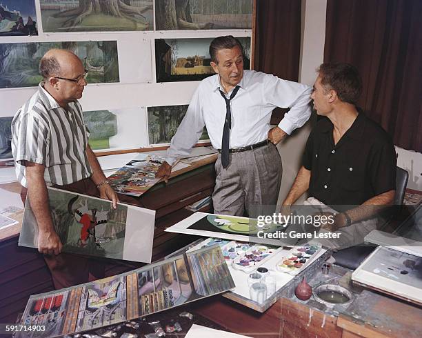American movie producer, artist, and animator Walt Disney talks with a pair of unidentified animators about some of their work, California, 1950s.