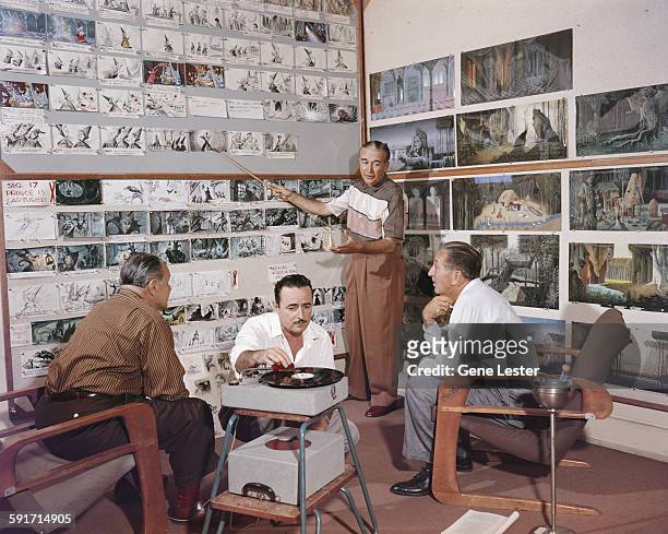 American movie producer, artist, and animator Walt Disney listens to an unidentified animator talk through the storyboards for the film 'Sleeping...