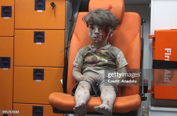 Year-old wounded Syrian kid Omran Daqneesh sits alone in the back of the ambulance after he got injured during Russian or Assad regime forces air...