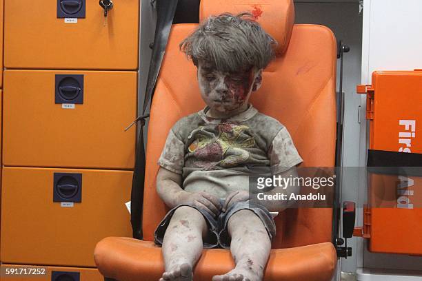 Year-old wounded Syrian kid Omran Daqneesh sits alone in the back of the ambulance after he got injured during Russian or Assad regime forces air...
