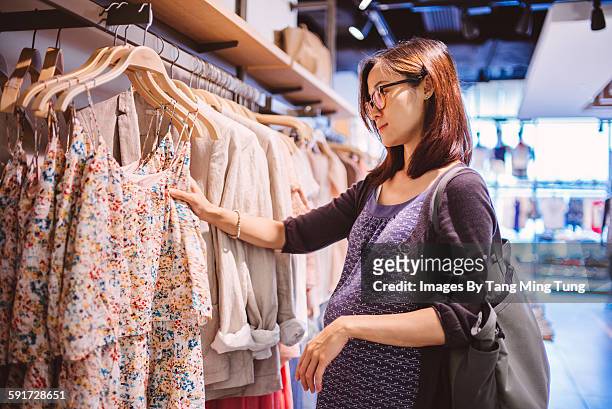 pregnant lady shopping for clothing in a boutique - maternity wear 個照片及圖片檔