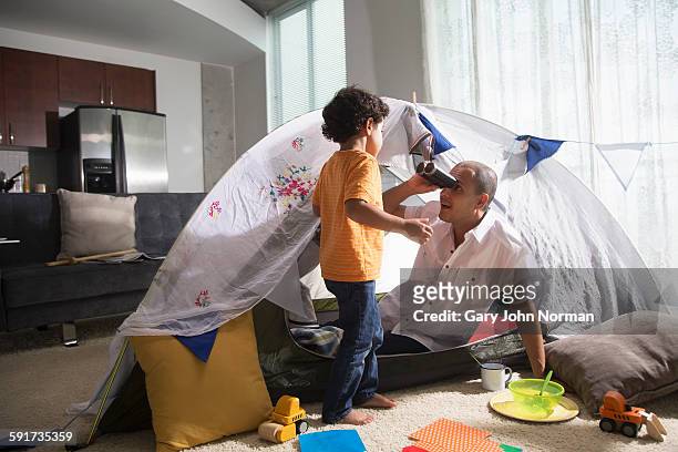 dad plays at camping indoors with young son - norman window fotografías e imágenes de stock