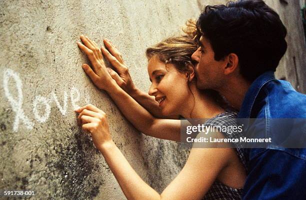 couple writing 'love' in chalk on wall, close-up - chalk wall stock pictures, royalty-free photos & images