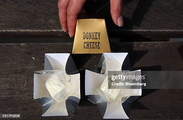 An employee displays the gold packaging for 50 gram blocks of Serbian donkey cheese, locally known as pule, which retail for 50-70 euros at the...