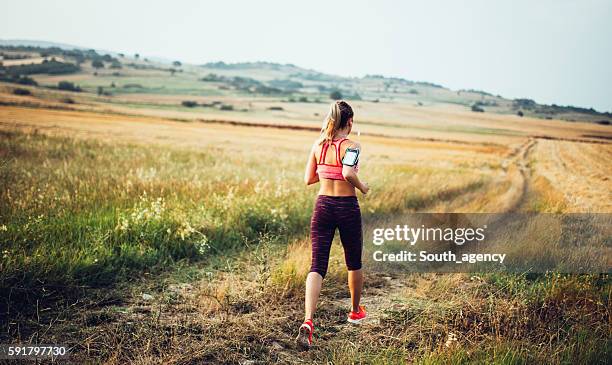 fare jogging sul campo e ascoltare musica - running shorts foto e immagini stock