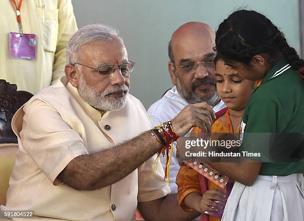 Children tie rakhi on the wrist of Prime Minister Narendra Modi while BJP President Amit Shah looks on after Bhoomi Poojan of new Headquarter of BJP...