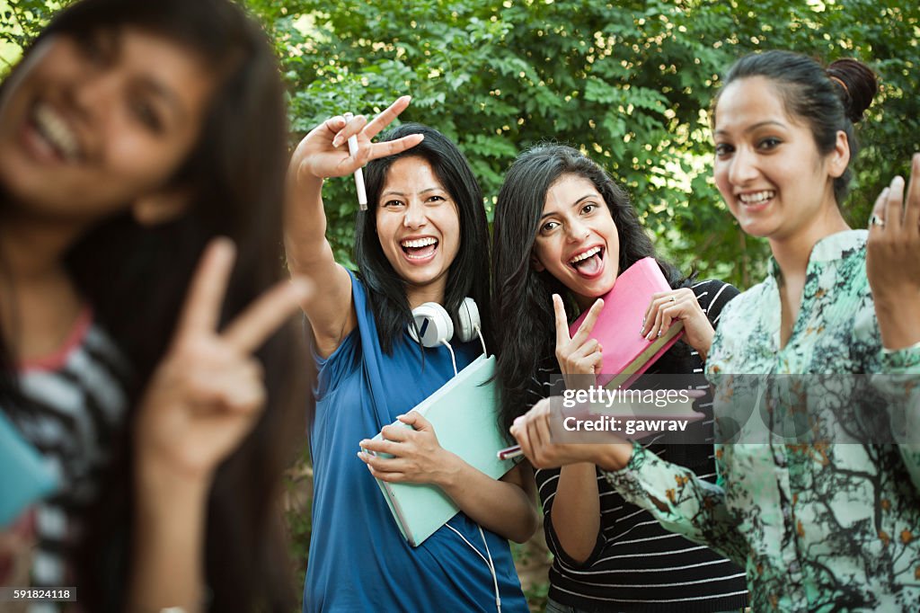 Group of Happy girl students showing peace hand sign.