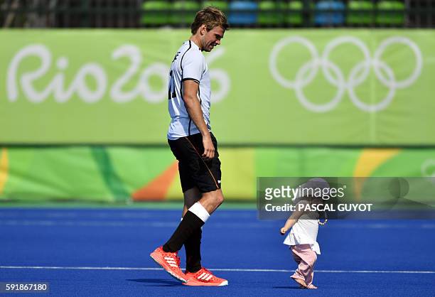 Germany's Moritz Furste walks on the pitch with his child after winning the men's Bronze medal field hockey Netherlands vs Germany match of the Rio...