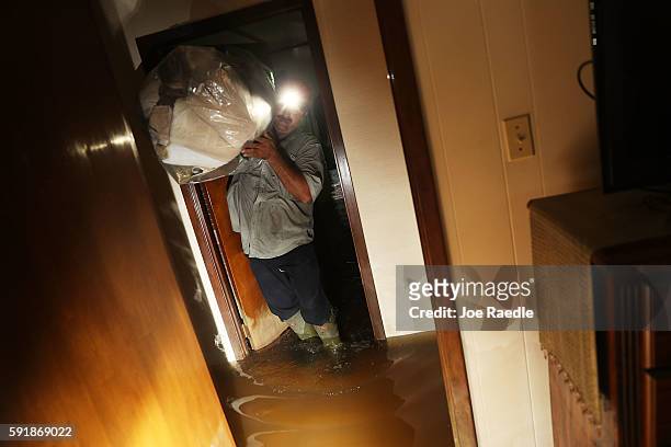 Jason Badon salvages what he can from his friends flooded home on August 18, 2016 in St Amant, Louisiana. Last week Louisiana was overwhelmed with...