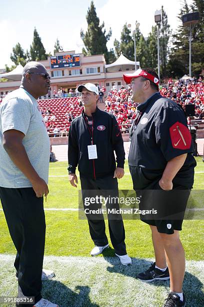 Charles Haley walks with General Manager Trent Baalke and Assistant General Manager Tom Gamble of the San Francisco 49ers talk on the field prior to...