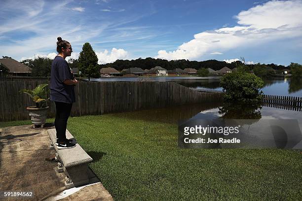 Nicole Howell looks at the receding flood waters from behind her father's home on August 18, 2016 in St Amant, Louisiana. Last week Louisiana was...