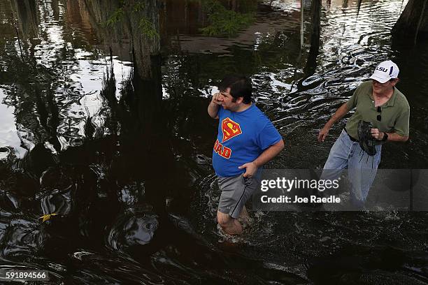 People walk along a flooded street on August 18, 2016 in St Amant, Louisiana. Last week Louisiana was overwhelmed with flood water causing at least...