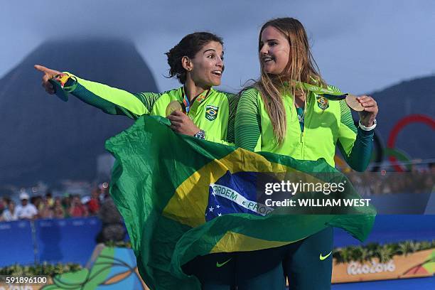 Gold medallists Brazil's Martine Grael and Brazil's Kahena Kunze celebrate on the podium of the 49er FX Women medal race at Marina da Gloria during...