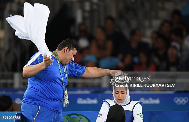 Staff members holds an ice pack on the head of Iran's Kimia Alizadeh Zenoorin during a break as she competes against Sweden's Nikita Glasnovic during...